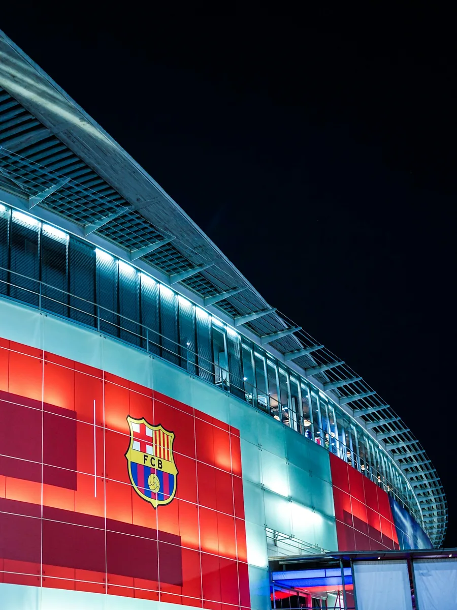 La façade illuminée du stade du FC Barcelone, avec l'écusson du club, de nuit