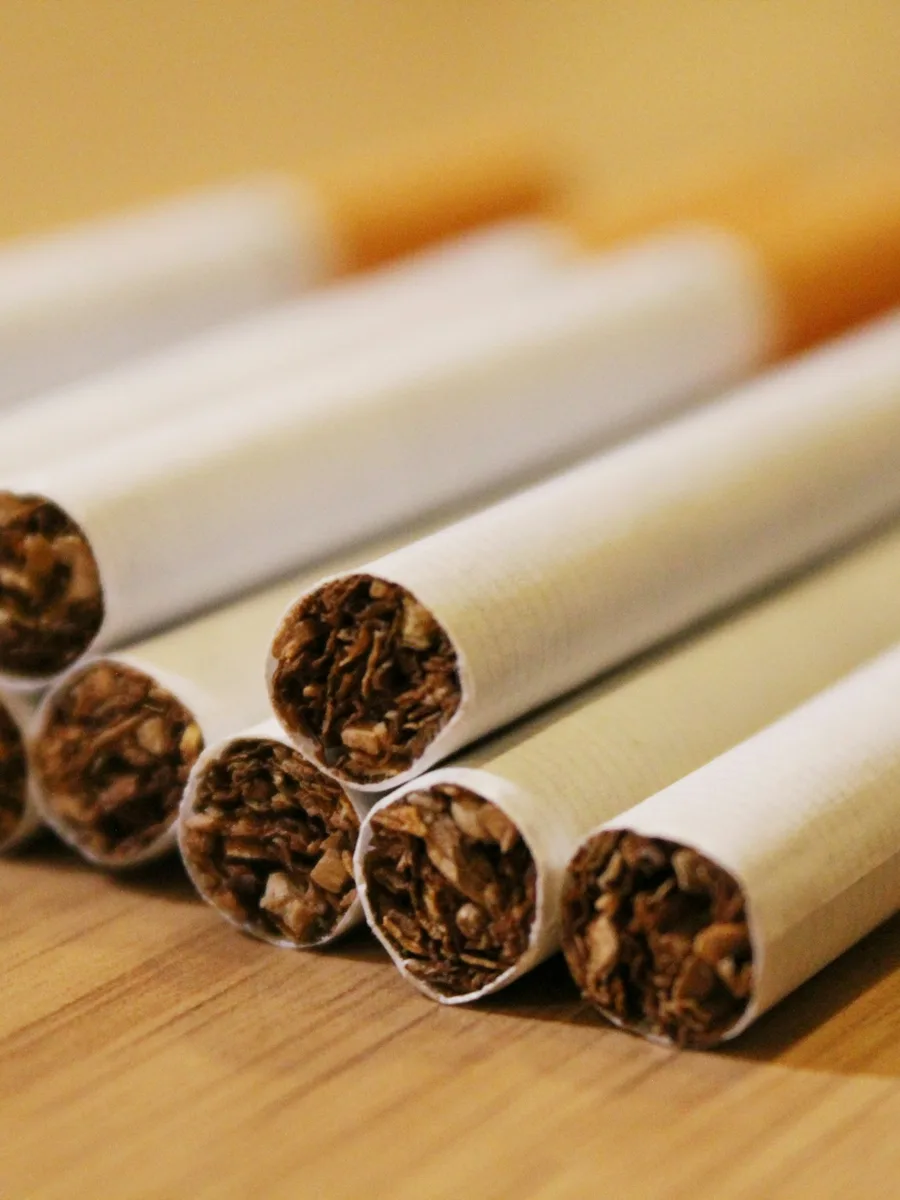 Cigarettes posées en vrac sur une table en bois, vues de près